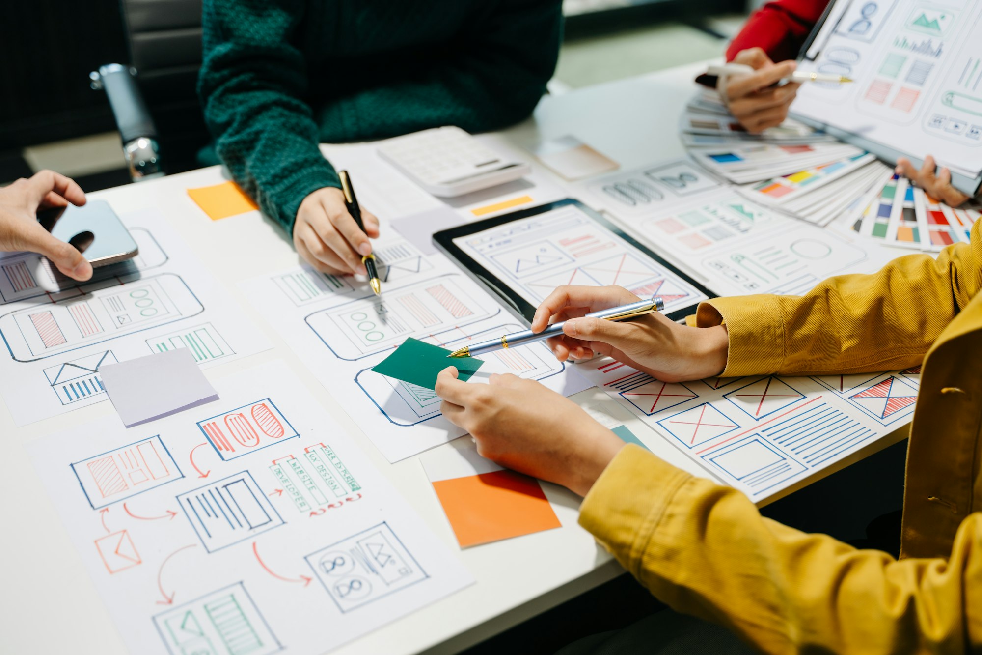 Close up view of UI developer team brainstorming on their project with laptop, smartphone